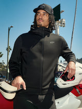 Alpinestars Cypher Hoodie, felpa lifestyle in pile nero con zip, cappuccio a collo alto con logo, piccolo logo Astars bianco sul petto, indossata con un cappellino nero da un pilota con un casco da motocross bianco, streetwear casual motorsport