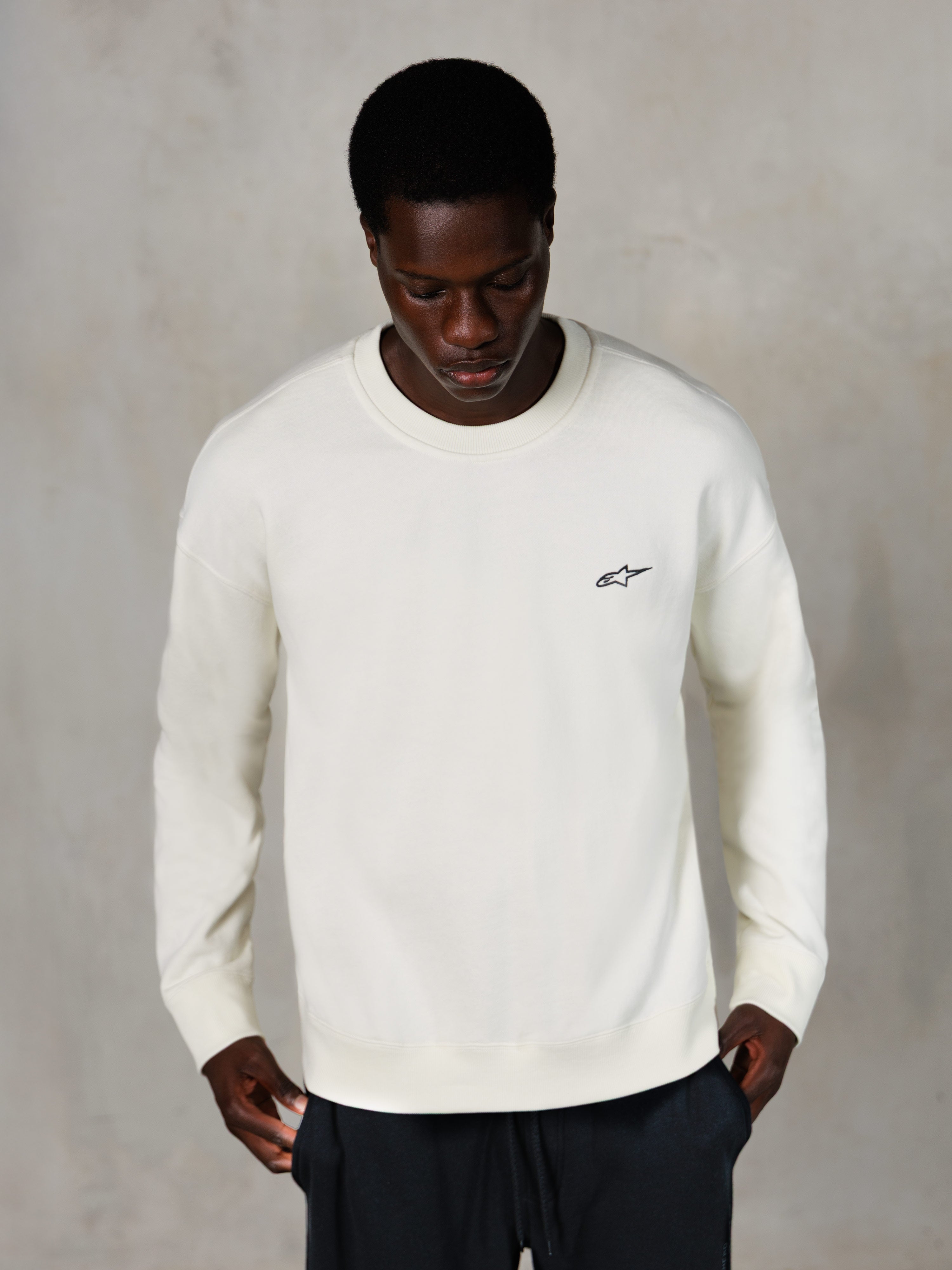 Alpinestars Essentials Ageless Crew, felpa girocollo, Off White, piccolo logo Alpinestars nero sul petto, indossata da un modello, streetwear casual lifestyle, morbido pile premium