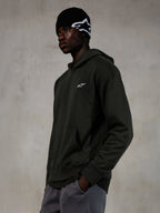 Felpa con cappuccio Alpinestars Essentials Ageless, Off Black, modello che indossa streetwear casual, pile grigio antracite con finitura stone wash e piccolo logo a stella bianco, abbinata a un berretto Alpinestars nero e pantaloni grigi