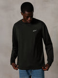 Alpinestars Essentials Ageless LS Tee, t-shirt a maniche lunghe, Off Black, con un piccolo logo bianco sul petto, indossata da un modello con jeans blu, stile streetwear casual