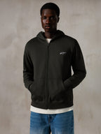 Alpinestars Essentials Ageless Zip Hoodie, Off Black, felpa con cappuccio e zip con un piccolo logo Alpinestars bianco sul petto, vestibilità rilassata, indossata da un modello con jeans blu e una t-shirt bianca, streetwear casual ispirato al motorsport