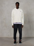Felpa con cappuccio e zip Alpinestars Essentials Ageless, streetwear casual, bianco sporco con discreto logo nero sul petto, chiusura frontale con zip, design con cappuccio, vestibilità rilassata, abbinata a pantaloni sportivi neri e sneakers