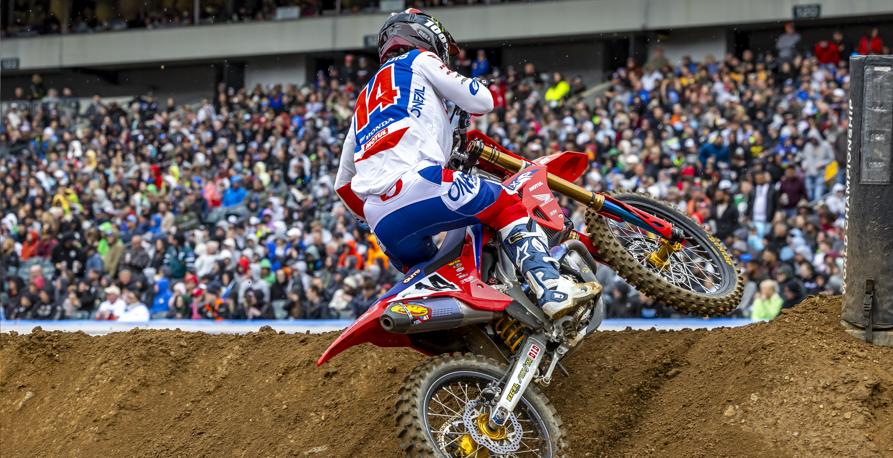 Motocross rider Dylan Ferrandis performing a jump on a dirt track with a crowd in the background, while wearing Alpinestars Tech 10 Boots