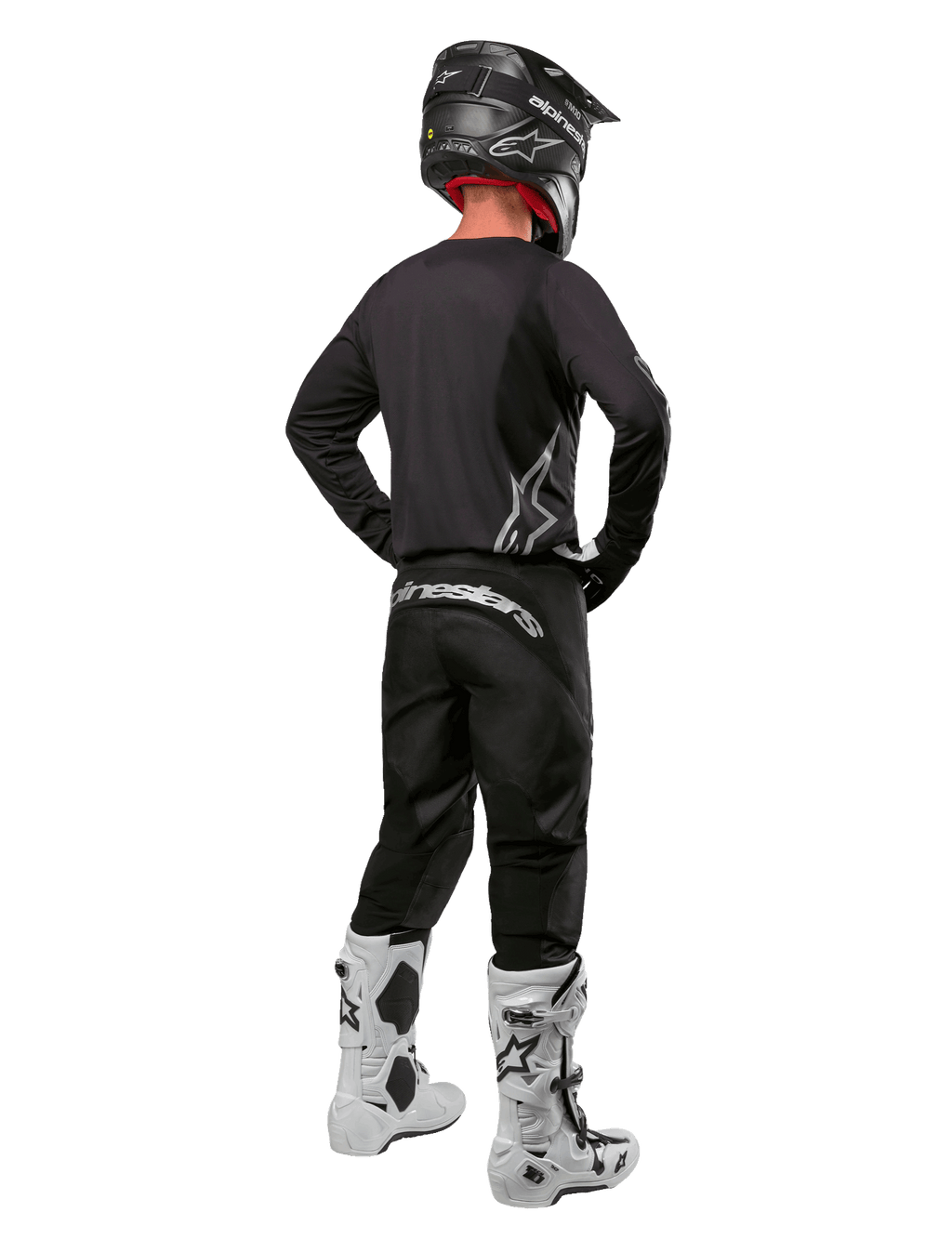 Set completo Alpinestars Fluid Graphite 2024, pilota di motocross visto di spalle, maglia e pantaloni grigio grafite con logo Alpinestars argento, casco nero e stivali da motocross bianchi, abbigliamento con vestibilità atletica per la guida fuoristrada