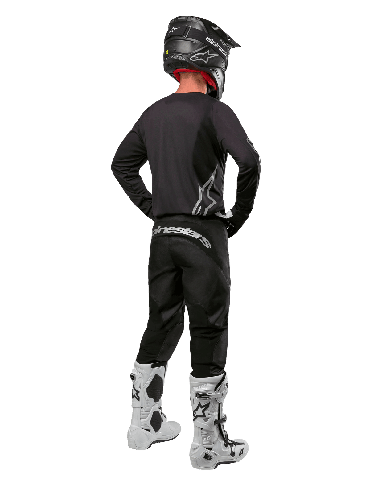 Set completo Alpinestars Fluid Graphite 2024, pilota di motocross visto di spalle, maglia e pantaloni grigio grafite con logo Alpinestars argento, casco nero e stivali da motocross bianchi, abbigliamento con vestibilità atletica per la guida fuoristrada