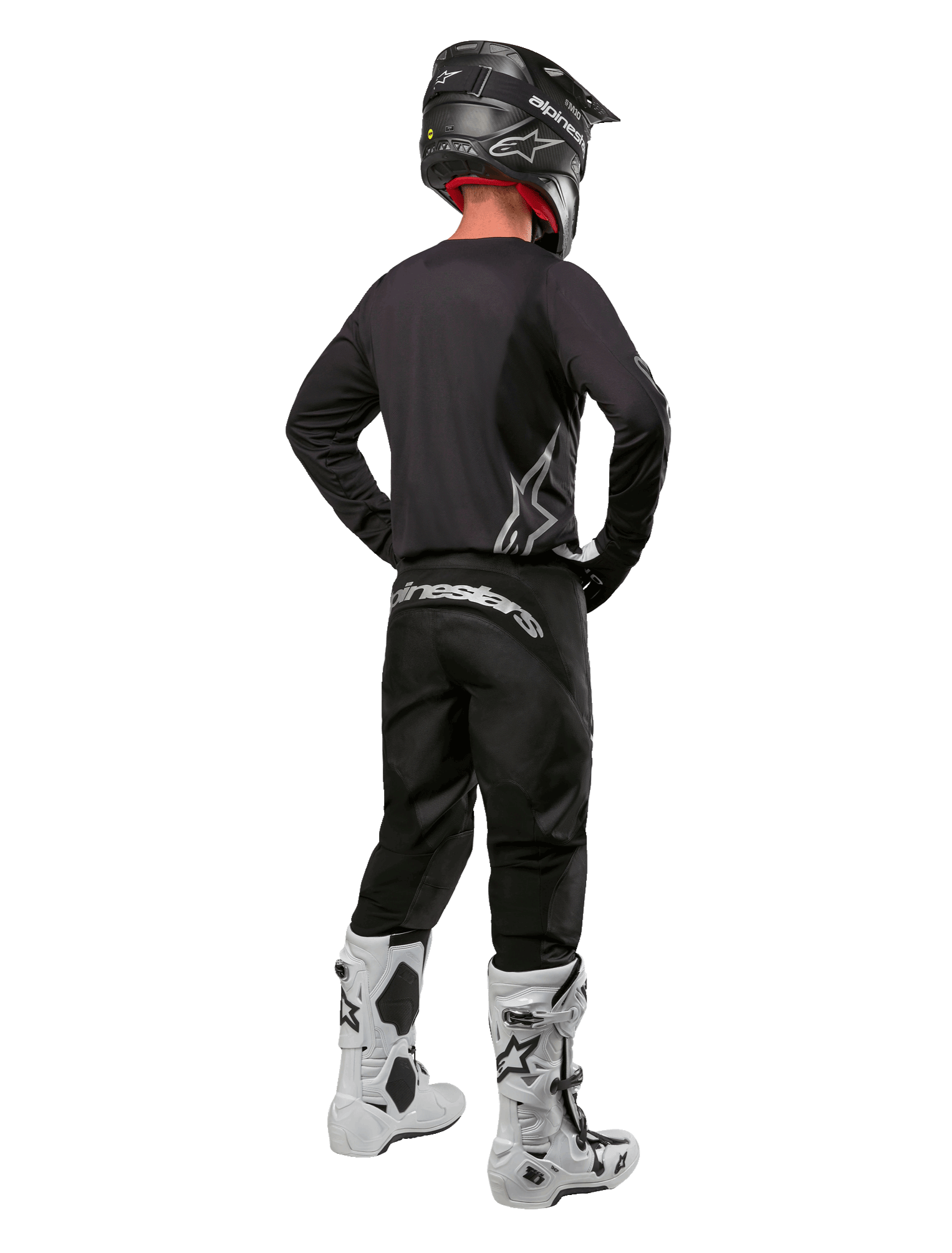 Set completo Alpinestars Fluid Graphite 2024, pilota di motocross visto di spalle, maglia e pantaloni grigio grafite con logo Alpinestars argento, casco nero e stivali da motocross bianchi, abbigliamento con vestibilità atletica per la guida fuoristrada