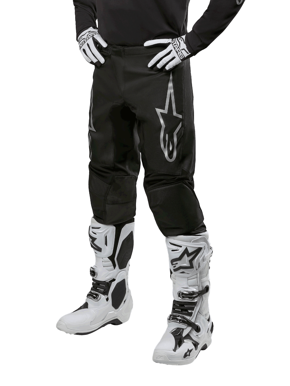 Alpinestars 2024 Fluid Graphite Pants, pantaloni da motocross, nero e argento, con logo Alpinestars argento sulla coscia, mostrati indossati con stivali e guanti da motocross bianchi, progettati per corse motociclistiche fuoristrada