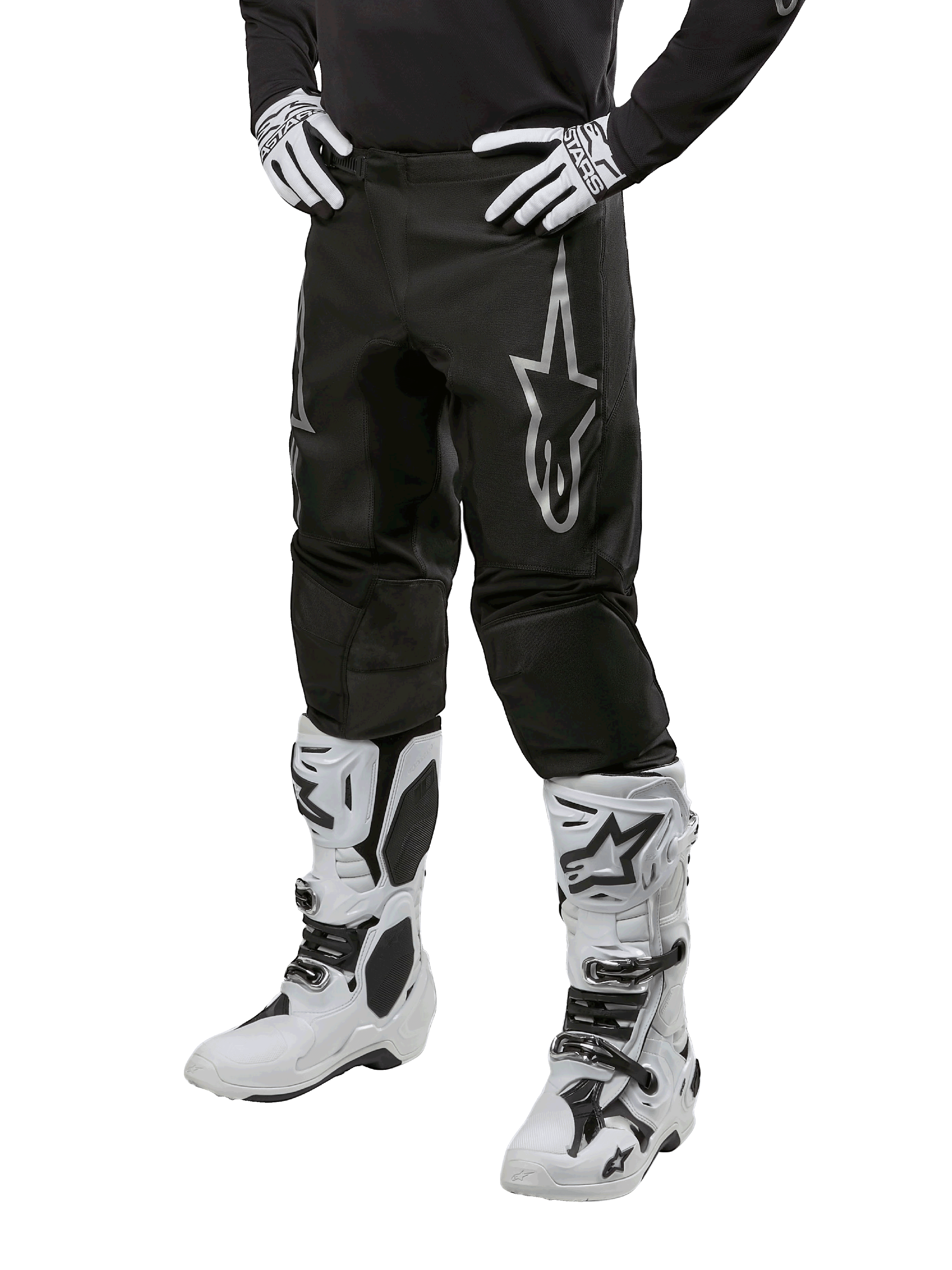 Alpinestars 2024 Fluid Graphite Pants, pantaloni da motocross, nero e argento, con logo Alpinestars argento sulla coscia, mostrati indossati con stivali e guanti da motocross bianchi, progettati per corse motociclistiche fuoristrada