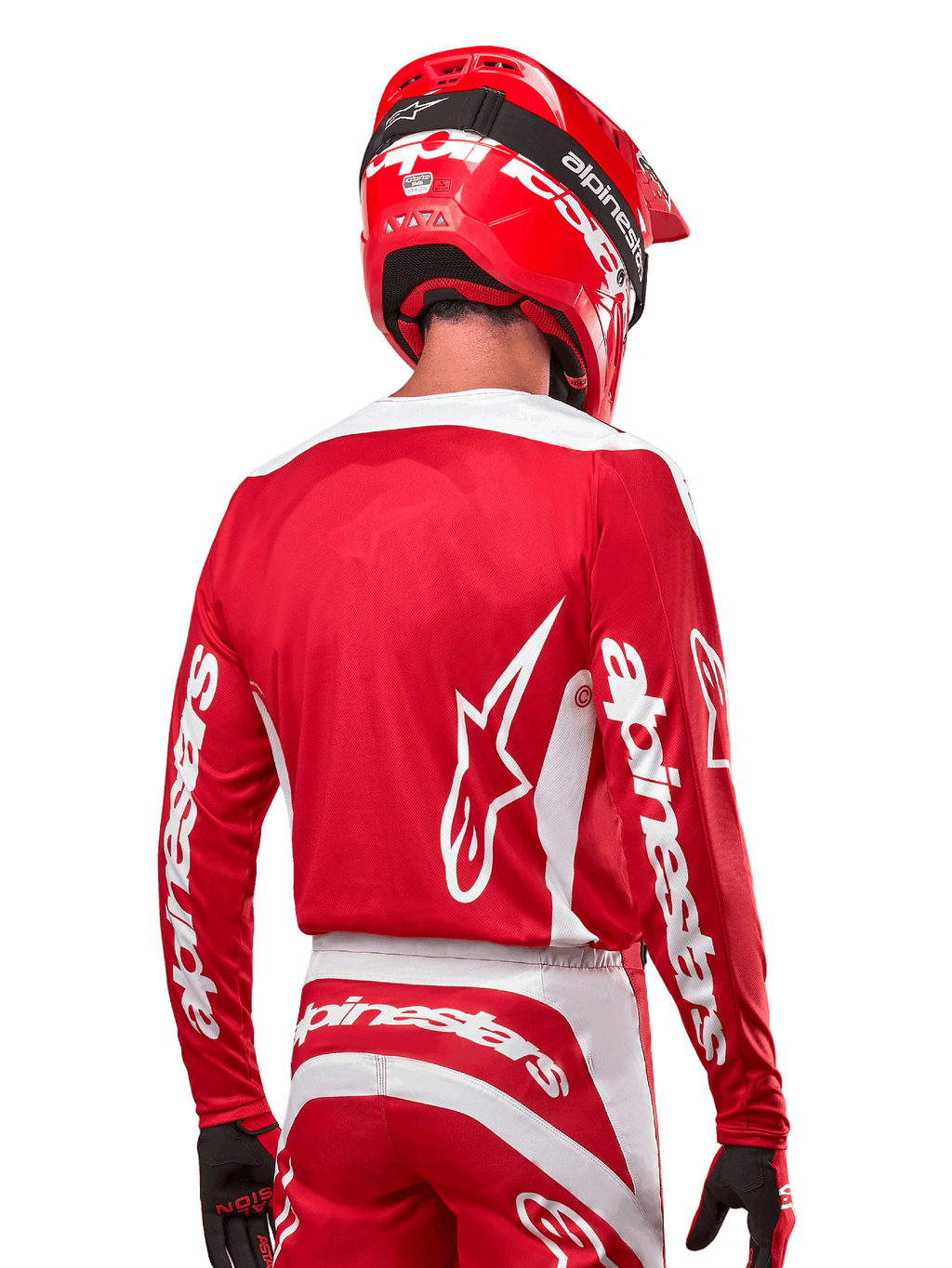 Pilota di motocross con maglia Alpinestars Fluid Lurv 2024, rosso Marte e bianco, vista posteriore con logo Alpinestars bianco sulla schiena e marchio sulle maniche, abbinata a casco rosso e guanti neri, abbigliamento professionale da corsa off-road
