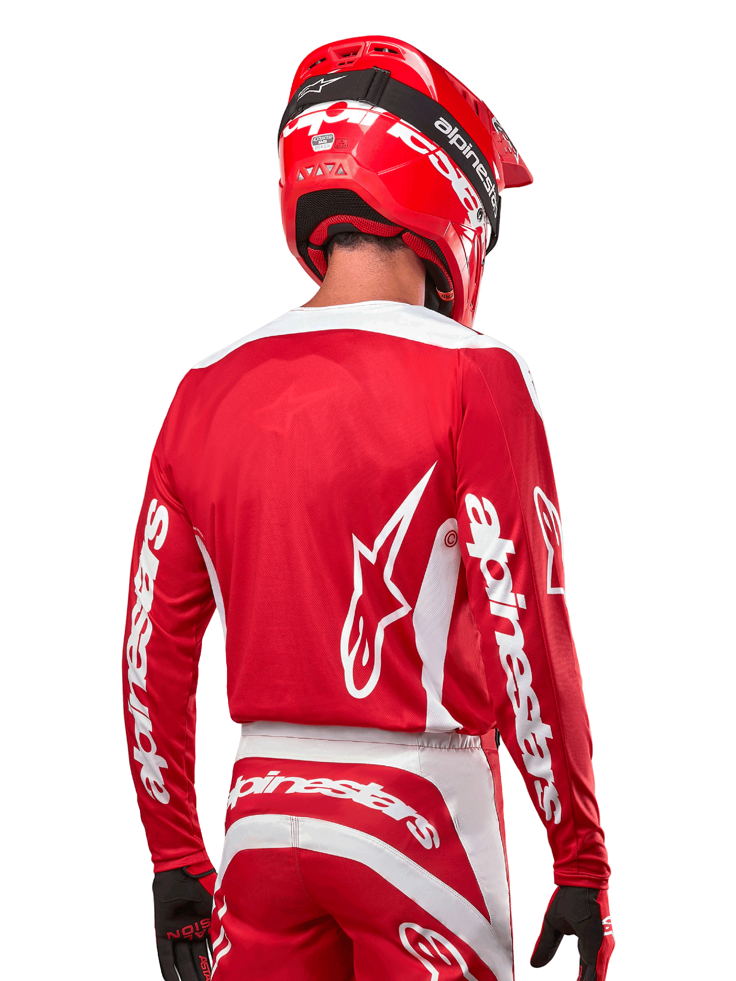 Pilota di motocross con maglia Alpinestars Fluid Lurv 2024, rosso Marte e bianco, vista posteriore con logo Alpinestars bianco sulla schiena e marchio sulle maniche, abbinata a casco rosso e guanti neri, abbigliamento professionale da corsa off-road