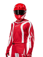 Alpinestars Maglia Fluid Lurv 2024, maglia da motocross, rosso Mars e bianco, indossata con casco e guanti coordinati, design sportivo audace con strisce curve bianche e marchio Alpinestars