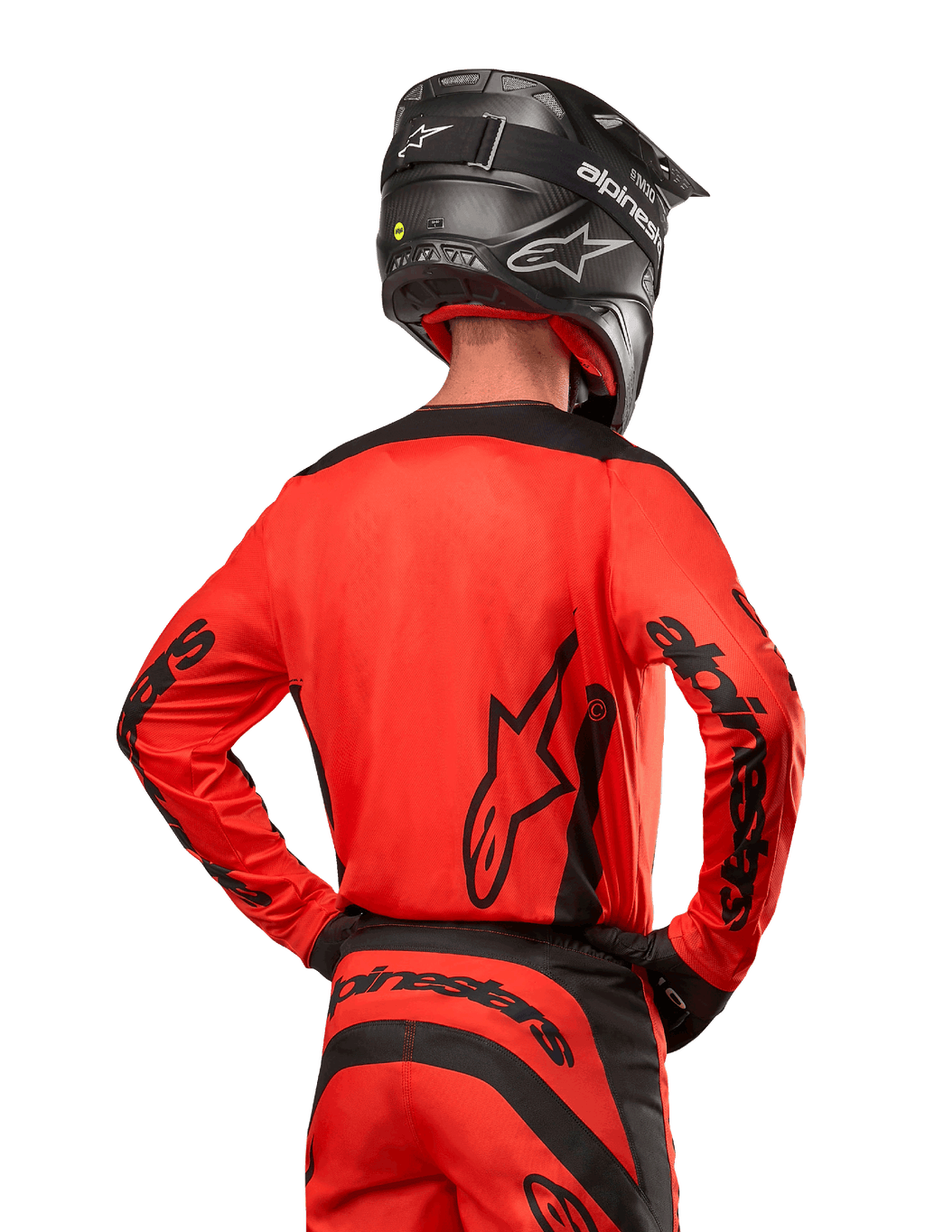 Pilota di motocross visto da dietro con maglia Alpinestars Fluid Lurv 2024 in Hot Orange e nero, loghi Alpinestars su schiena e maniche, abbinata a pantaloni da motocross coordinati e casco nero, progettata per prestazioni off-road.