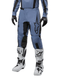 Pantaloni Alpinestars Fluid Lurv 2024, pantaloni da motocross blu chiaro e nero, indossati con maglia a maniche lunghe coordinata e stivali da motocross bianchi, caratterizzati da un evidente logo a stella nero sulla coscia e pannelli interni rinforzati sulle ginocchia, vista frontale su sfondo bianco.
