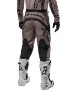Alpinestars 2024 Fluid Lurv Pants, pantaloni da motocross, Mud Black, vista posteriore con grande logo Alpinestars nero sulla seduta e pannelli neri sui polpacci, indossati con stivali da motocross bianchi e neri e maglia coordinata