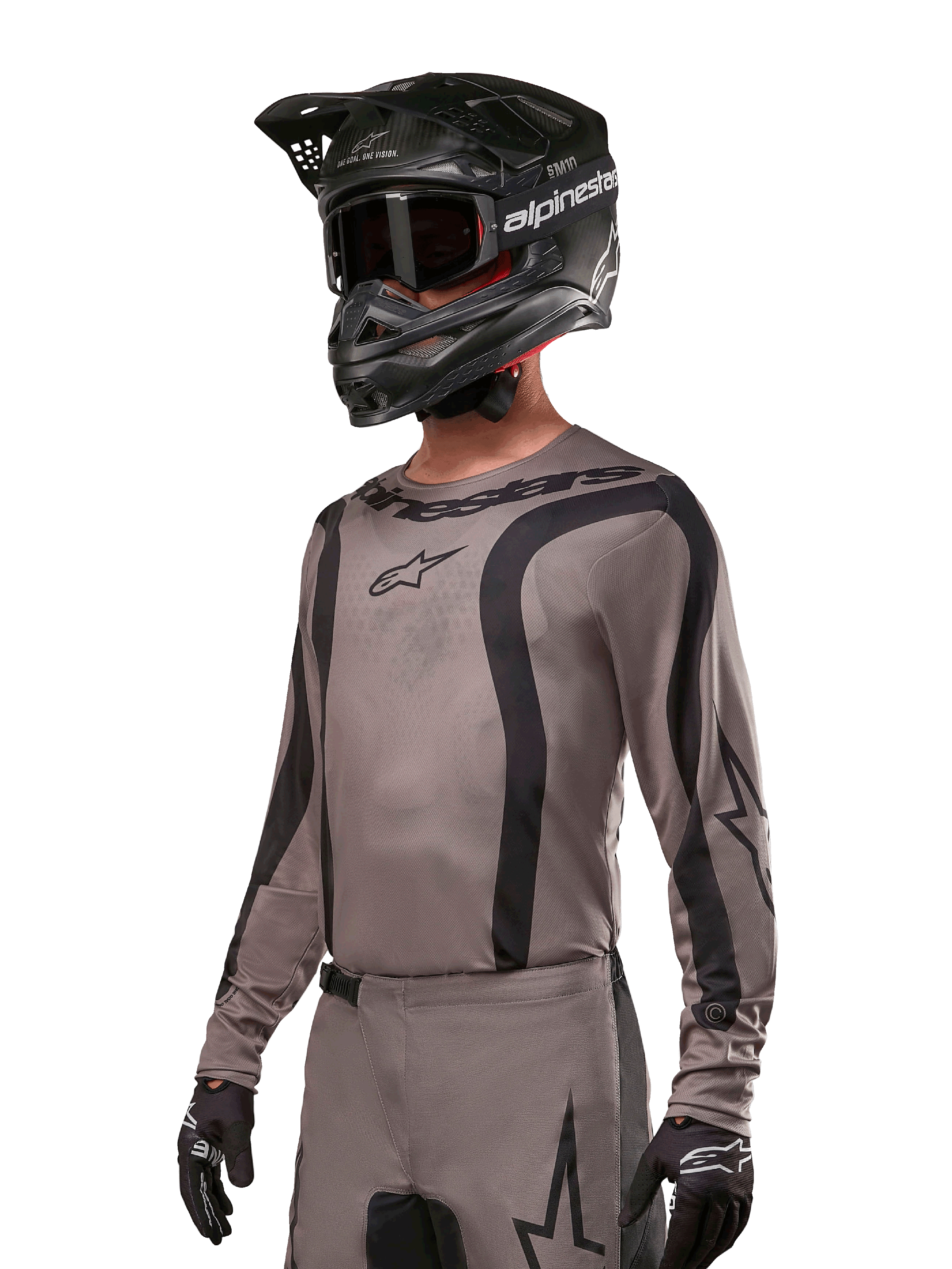 Maglia Alpinestars 2024 Fluid Lurv, maglia da motocross, Mud Black e grigio, design a maniche lunghe con strisce nere curve e loghi, indossata con pantaloni coordinati e un casco da motocross nero, kit da gara fuoristrada coordinato
