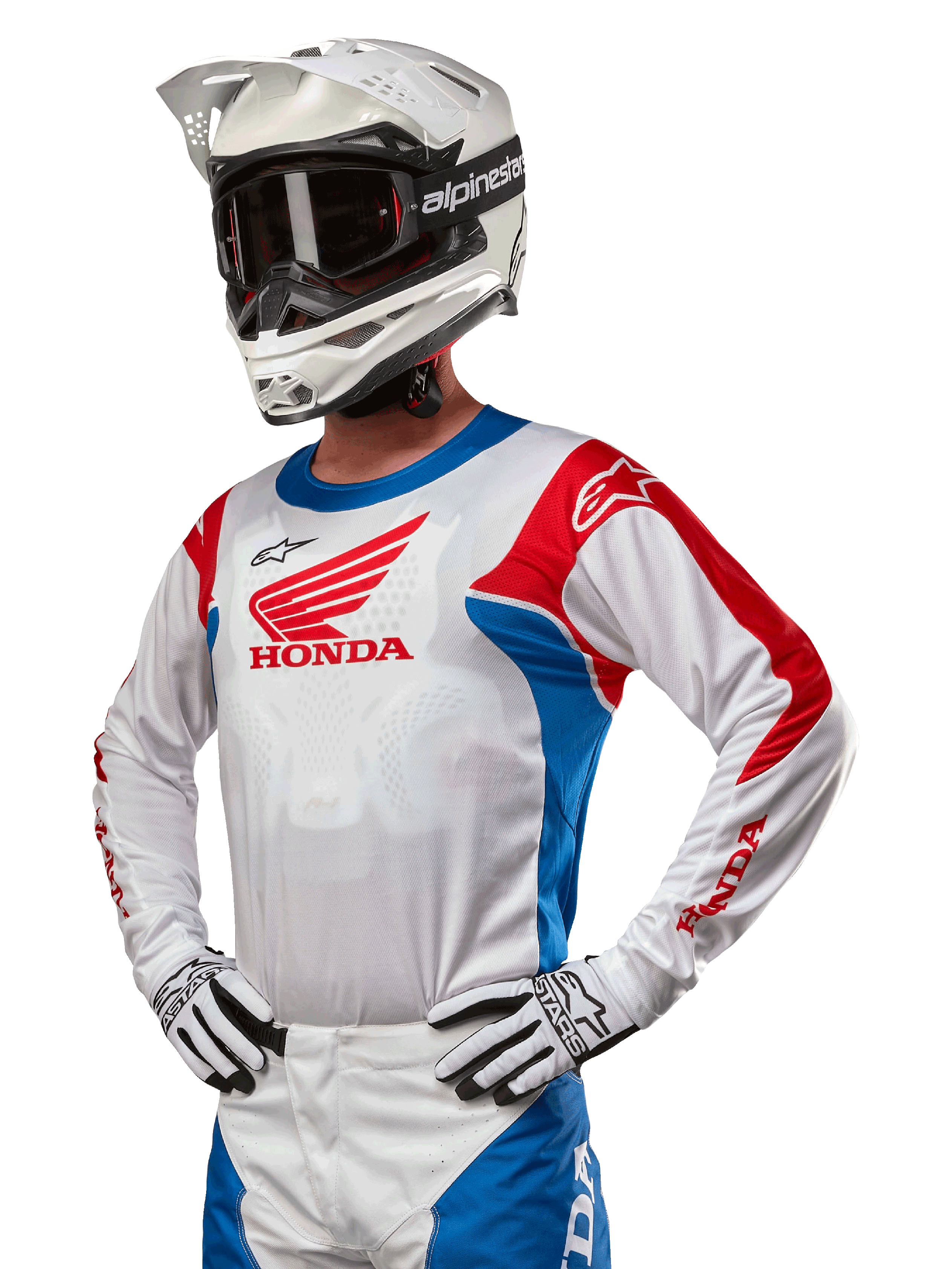 Pilota di motocross con maglia Honda Racer Iconic in bianco, blu brillante e rosso acceso, con un grande logo Honda sul petto, abbinata a un casco Alpinestars bianco e guanti bianchi e neri coordinati, equipaggiamento per prestazioni fuoristrada