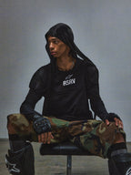 Alpinestars RSRV Nucleon SS Tee, t-shirt nera con logo RSRV bianco, stile streetwear urbano, indossata con pantaloni mimetici e protezioni
