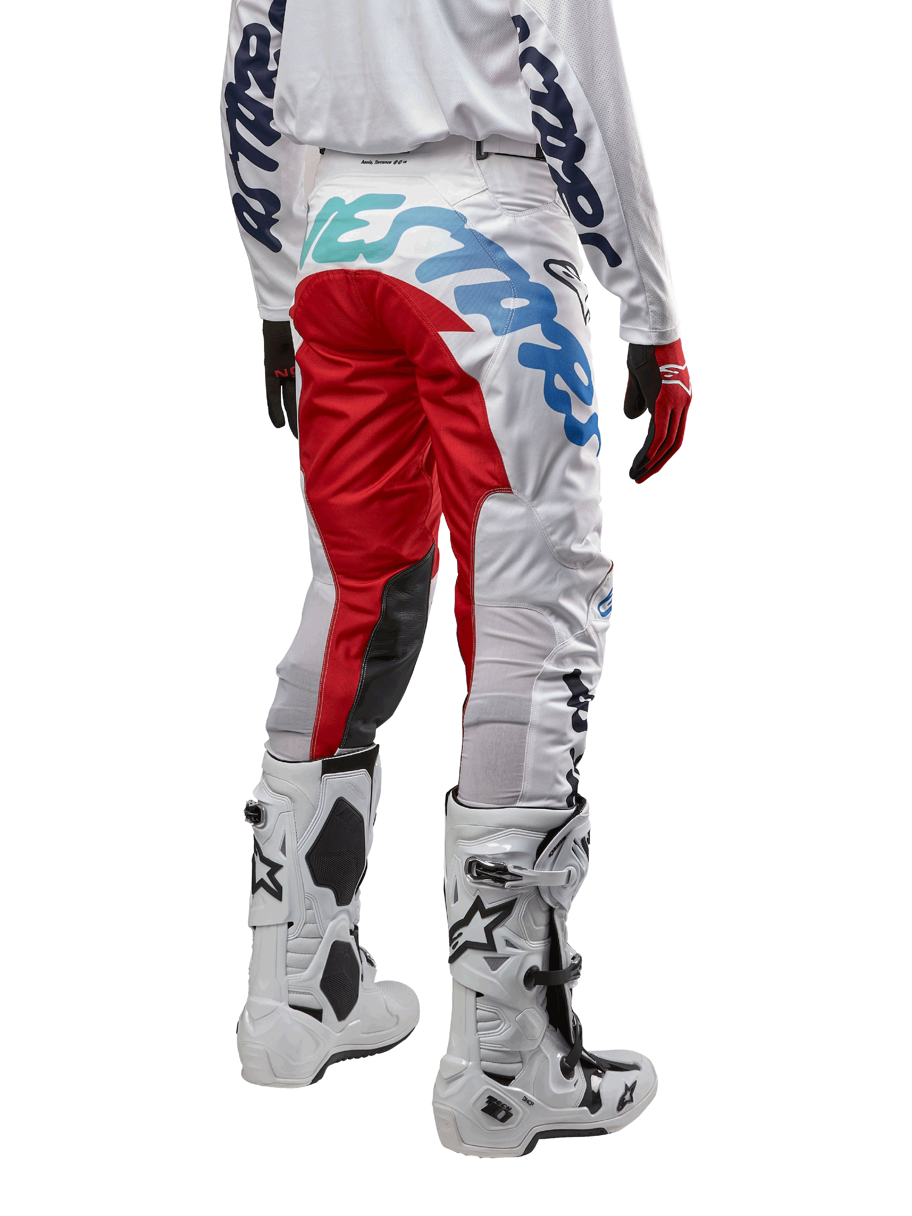 Alpinestars pantaloni Racer Hana 2024, pantaloni da motocross, bianco multicolore con accenti rossi e blu, vista posteriore con grande logo sulla seduta, indossati con stivali da motocross bianchi e neri, progettati per prestazioni e durata fuoristrada