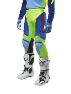 Pantaloni Alpinestars Racer Hoen 2024, pantaloni da motocross, giallo fluo e blu notte con loghi a stella rossi e pannelli interni neri alle ginocchia, indossati con maglia coordinata e stivali da motocross bianchi, abbigliamento tecnico per gare off-road