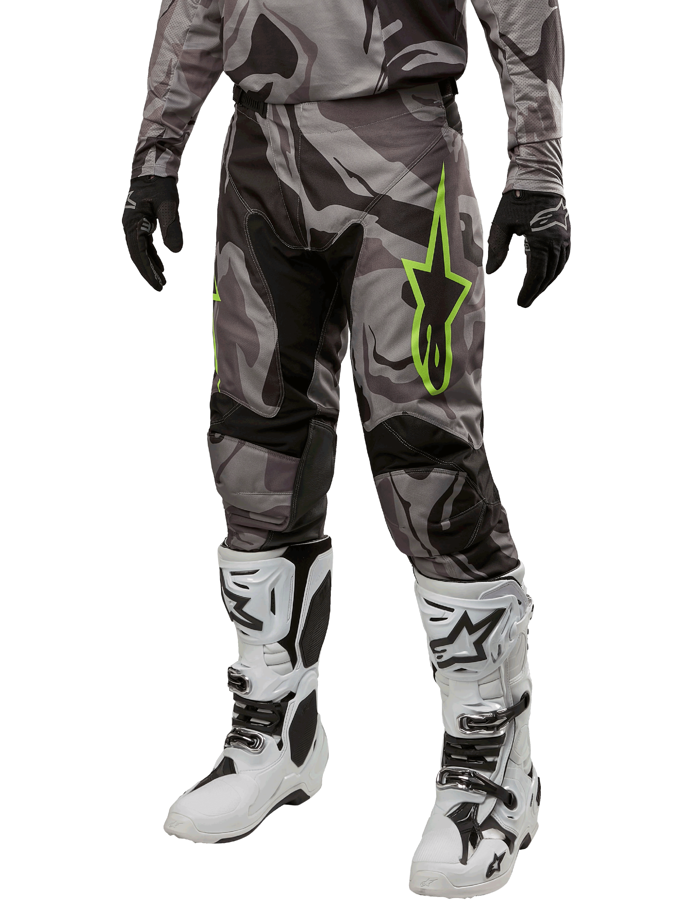 Alpinestars 2024 Racer Tactical Pants, pantaloni da motocross, pattern mimetico grigio e nero, logo a stella verde lime, indossati con stivali bianchi e neri e guanti neri, equipaggiamento per guida off-road