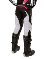 Alpinestars Stella Fluid Pant 2024 da donna, pantaloni da motocross, nero e bianco, vista posteriore che mostra pannelli bianchi sulle gambe e logo rosa sulla fascia in vita, indossati con stivali Tech 3 neri, equipaggiamento resistente per gare fuoristrada