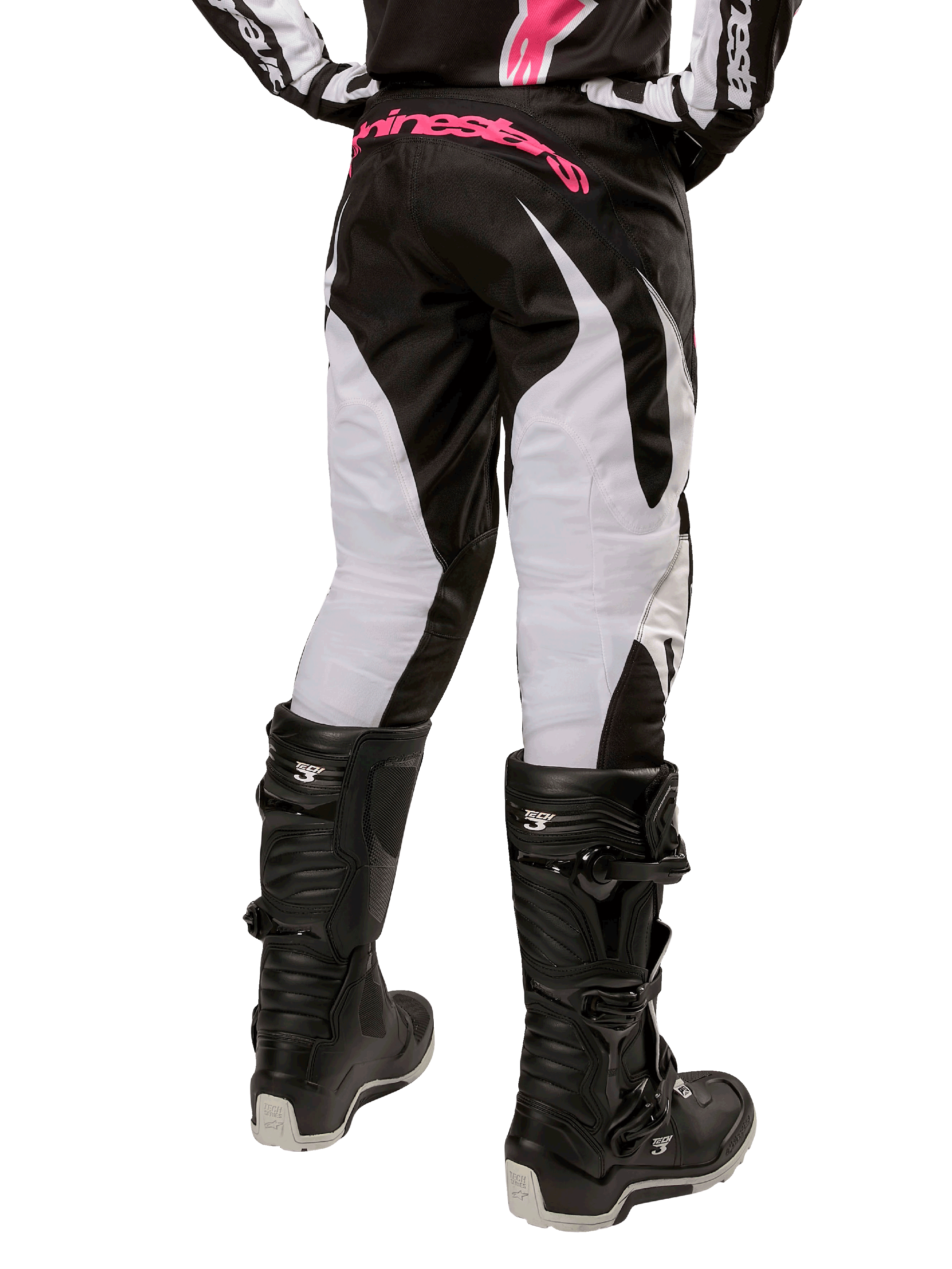 Alpinestars Stella Fluid Pant 2024 da donna, pantaloni da motocross, nero e bianco, vista posteriore che mostra pannelli bianchi sulle gambe e logo rosa sulla fascia in vita, indossati con stivali Tech 3 neri, equipaggiamento resistente per gare fuoristrada