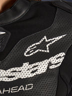 Primo piano della tuta in pelle Alpinestars Stella GP-R7 2 Pezzi in nero, caratterizzata da pannelli in pelle traforata, un grande logo Alpinestars bianco sul petto e sezioni in tessuto elastico traspirante.