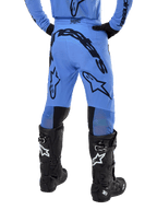 Pantaloni Alpinestars Supertech Dade 2024, pantaloni da motocross, blu chiaro, vista posteriore con grande marchio nero sulla seduta e sulle gambe, indossati con stivali neri Alpinestars Tech 10, vestibilità racing atletica per prestazioni professionali fuoristrada
