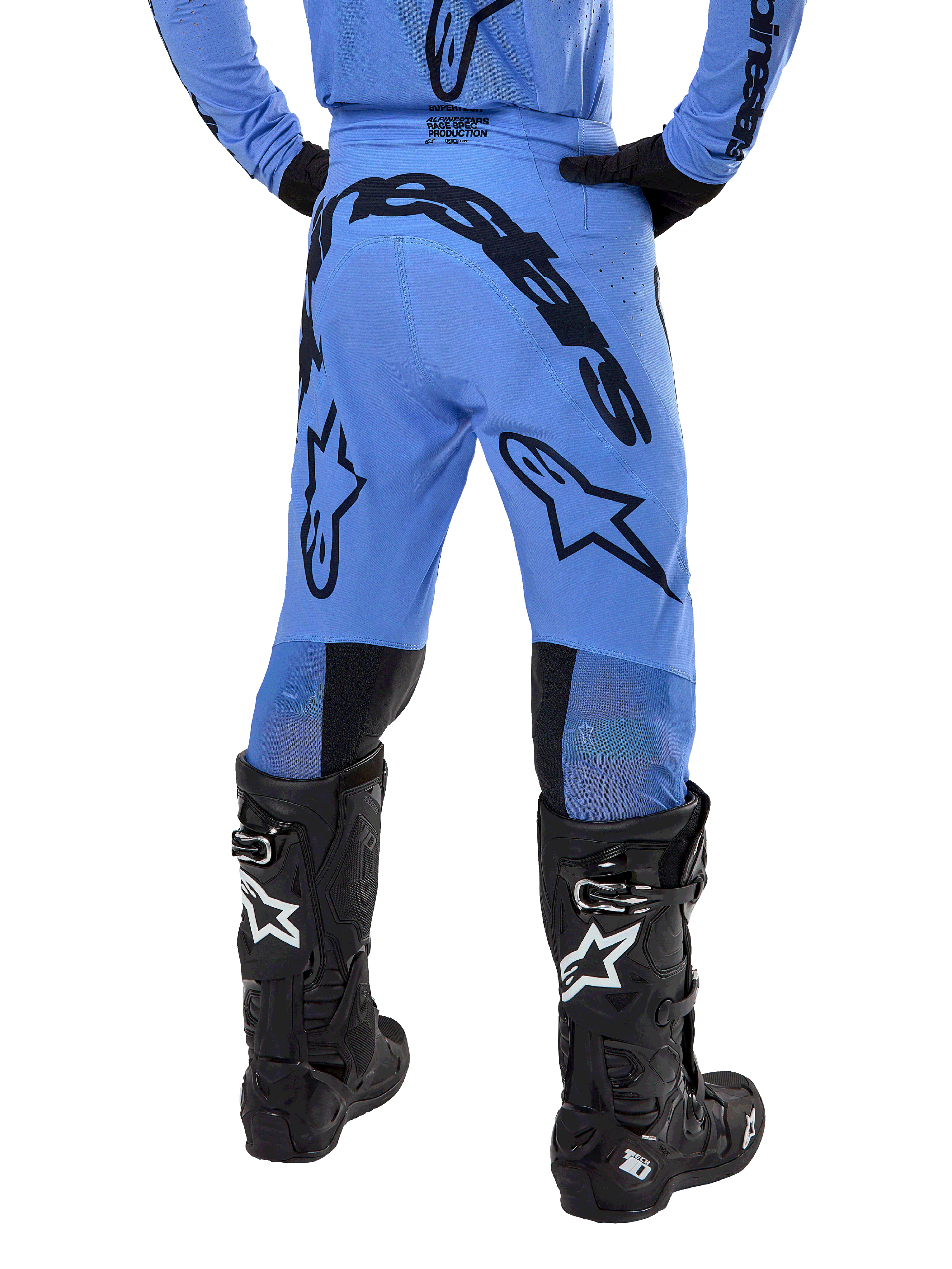 Pantaloni Alpinestars Supertech Dade 2024, pantaloni da motocross, blu chiaro, vista posteriore con grande marchio nero sulla seduta e sulle gambe, indossati con stivali neri Alpinestars Tech 10, vestibilità racing atletica per prestazioni professionali fuoristrada