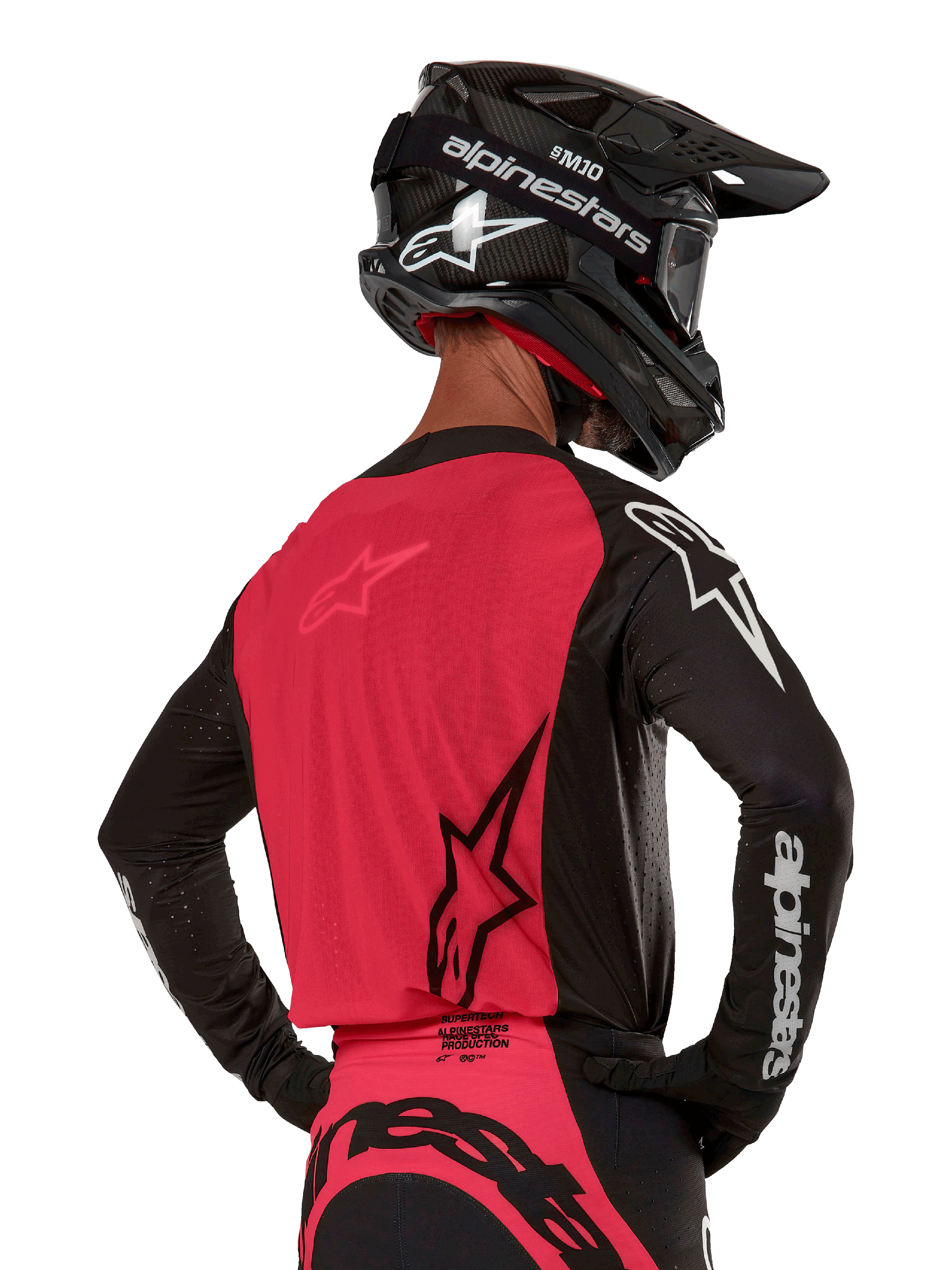 Alpinestars Supertech Ward Jersey 2024, maglia da motocross, nero e rosso berry, vista posteriore con pannello in rete rossa e maniche nere con marchio bianco, indossata con casco in fibra di carbonio nero e guanti, vestibilità race atletica per guida fuoristrada