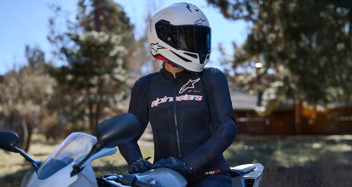 Alpinestars Stella SMX Air Jacket, Women's Motorcycle Jacket, Black, featuring breathable mesh ventilation panels, shoulder armor, and chest logo branding, worn by a rider on a motorcycle with a white helmet.