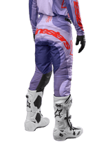 Alpinestars 2024 Techstar Ocuri Pants, pantaloni da motocross viola e arancione, vista posteriore, logo Alpinestars sul retro, indossati con stivali Tech 10 bianchi e guanti neri, equipaggiamento per fuoristrada