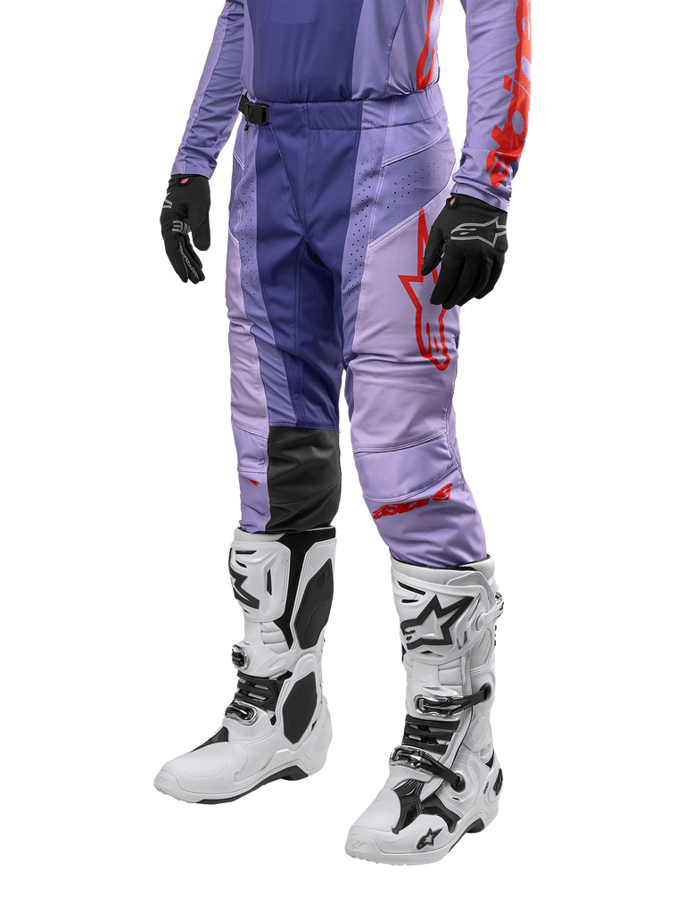 Alpinestars 2024 Techstar Ocuri Pants, pantaloni da motocross viola e arancione acceso, logo rosso, indossati con stivali da motocross bianchi e guanti neri, abbigliamento protettivo per fuoristrada