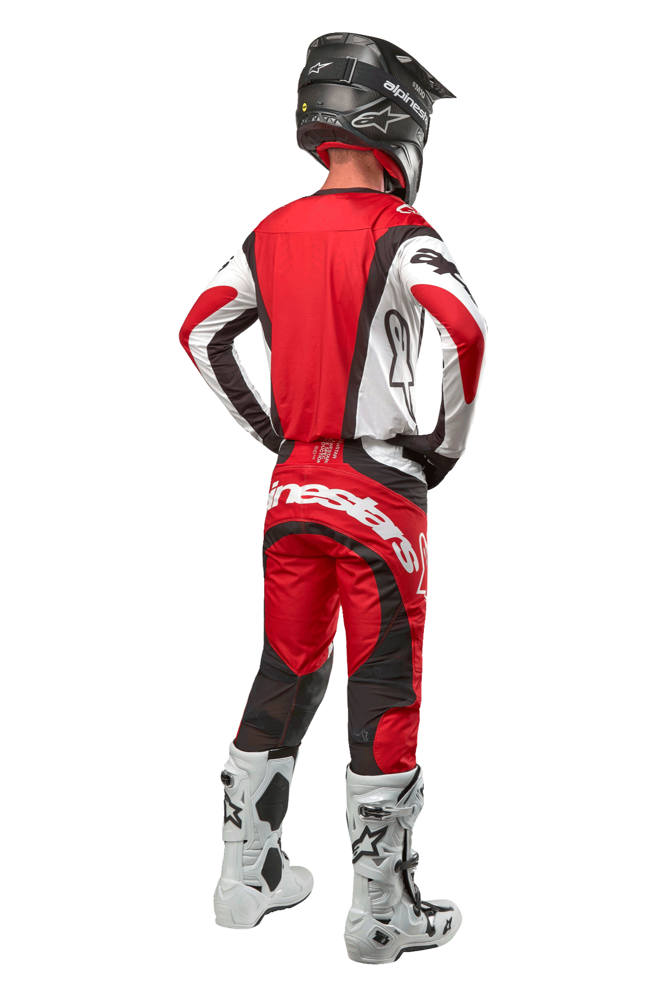 Alpinestars 2024 Techstar Ocuri Pants, pantaloni da motocross, rosso Mars, bianco e nero, vista posteriore di un pilota di motocross con attrezzatura da gara completa, inclusa maglia abbinata, casco nero e stivali bianchi e neri, mette in risalto il marchio Alpinestars e la struttura resistente.
