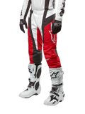Alpinestars Pantaloni Techstar Ocuri 2024, pantaloni da motocross, Rosso Marte, bianco e nero, indossati con maglia coordinata bianca e nera, guanti neri e stivali da corsa bianchi con fibbie, abbigliamento protettivo tecnico mostrato su sfondo bianco