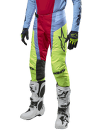 Alpinestars 2024 Techstar Ocuri Pants, pantaloni da motocross, azzurro, rosso berry e giallo neon, indossati con abbigliamento coordinato e stivali bianchi, con logo Astars in evidenza e una vestibilità racing performante.