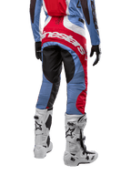 Alpinestars 2024 Techstar Ocuri Pants, pantaloni da motocross, azzurro, rosso Marte e bianco, vista posteriore che mette in risalto il grande logo Alpinestars rosso sulla seduta, indossati con stivali da gara bianchi e maglia coordinata.