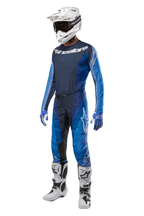 Pantaloni Alpinestars Techstar Pneuma 2024, pantaloni da motocross, blu scuro e azzurro, abbigliamento completo da gara con maglia coordinata, casco bianco con occhiali, guanti blu e bianchi e stivali bianchi, equipaggiamento professionale per fuoristrada