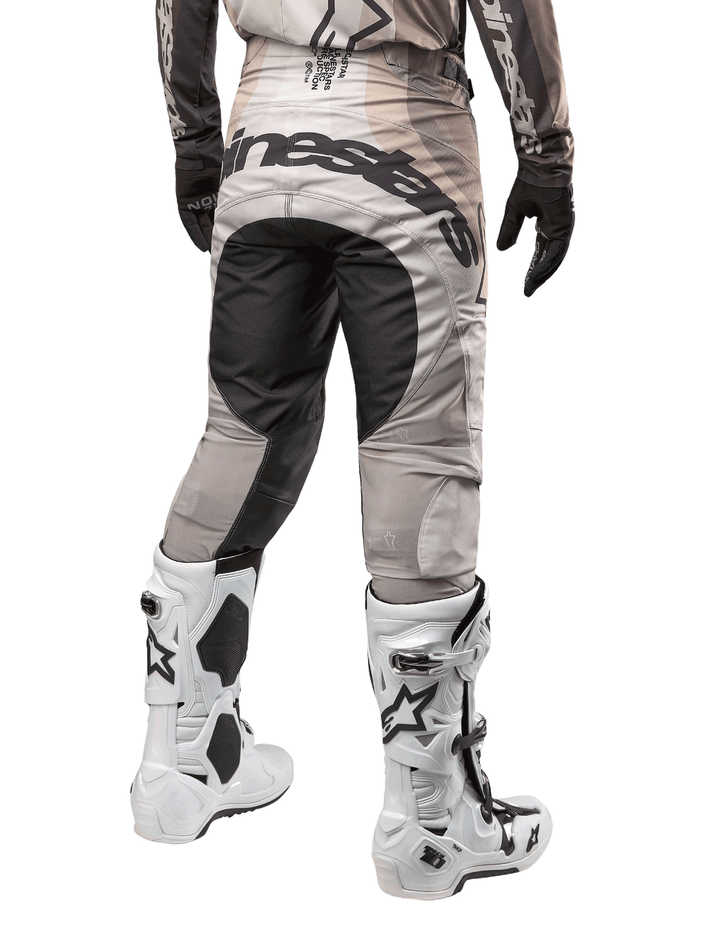 Pantaloni Alpinestars Techstar Pneuma 2024, pantaloni da motocross, Dark Sand e Iron Dust Gray, vista posteriore dalla vita in giù, vistoso logo Alpinestars nero sulla seduta, indossati con stivali da motocross bianchi e neri e guanti neri, design race-fit resistente per competizioni fuoristrada