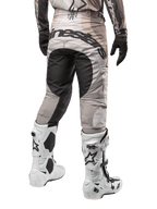 Pantaloni Alpinestars Techstar Pneuma 2024, pantaloni da motocross, Dark Sand e Iron Dust Gray, vista posteriore dalla vita in giù, vistoso logo Alpinestars nero sulla seduta, indossati con stivali da motocross bianchi e neri e guanti neri, design race-fit resistente per competizioni fuoristrada