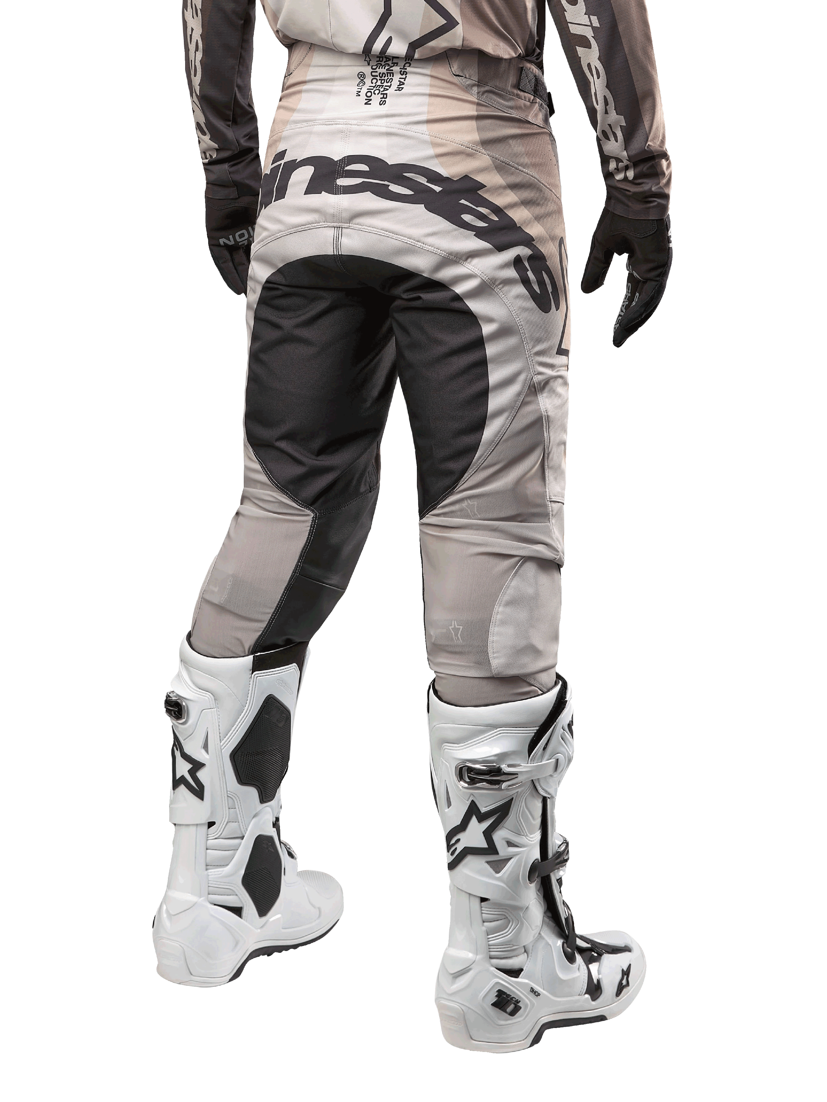 Pantaloni Alpinestars Techstar Pneuma 2024, pantaloni da motocross, Dark Sand e Iron Dust Gray, vista posteriore dalla vita in giù, vistoso logo Alpinestars nero sulla seduta, indossati con stivali da motocross bianchi e neri e guanti neri, design race-fit resistente per competizioni fuoristrada