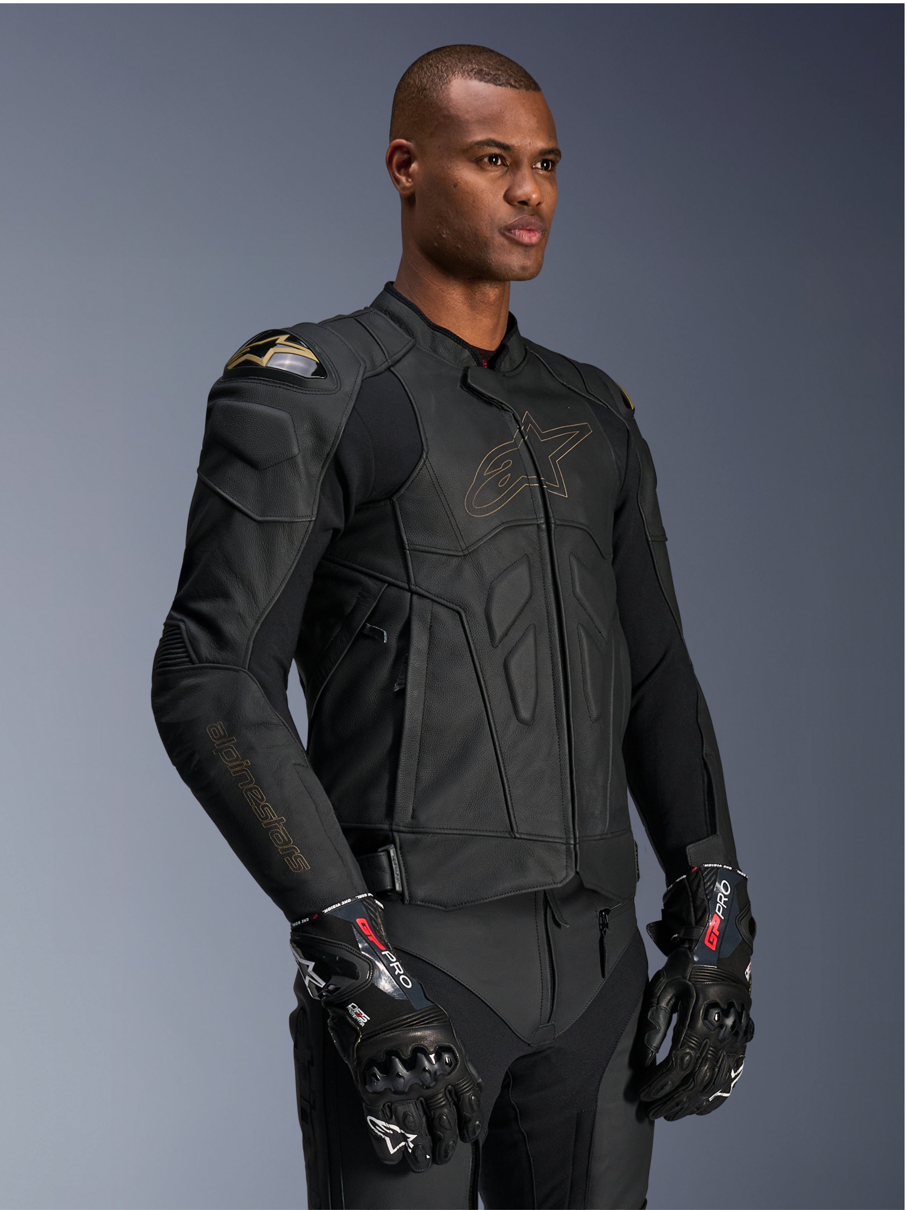Alpinestars Dusk Leather Jacket, giacca da moto Black Laser, costruzione in pelle pregiata con contorno del logo Alpinestars e marchio sulla manica in oro, protezione esterna per le spalle DFS, abbinata a guanti GP Pro, abbigliamento racing professionale