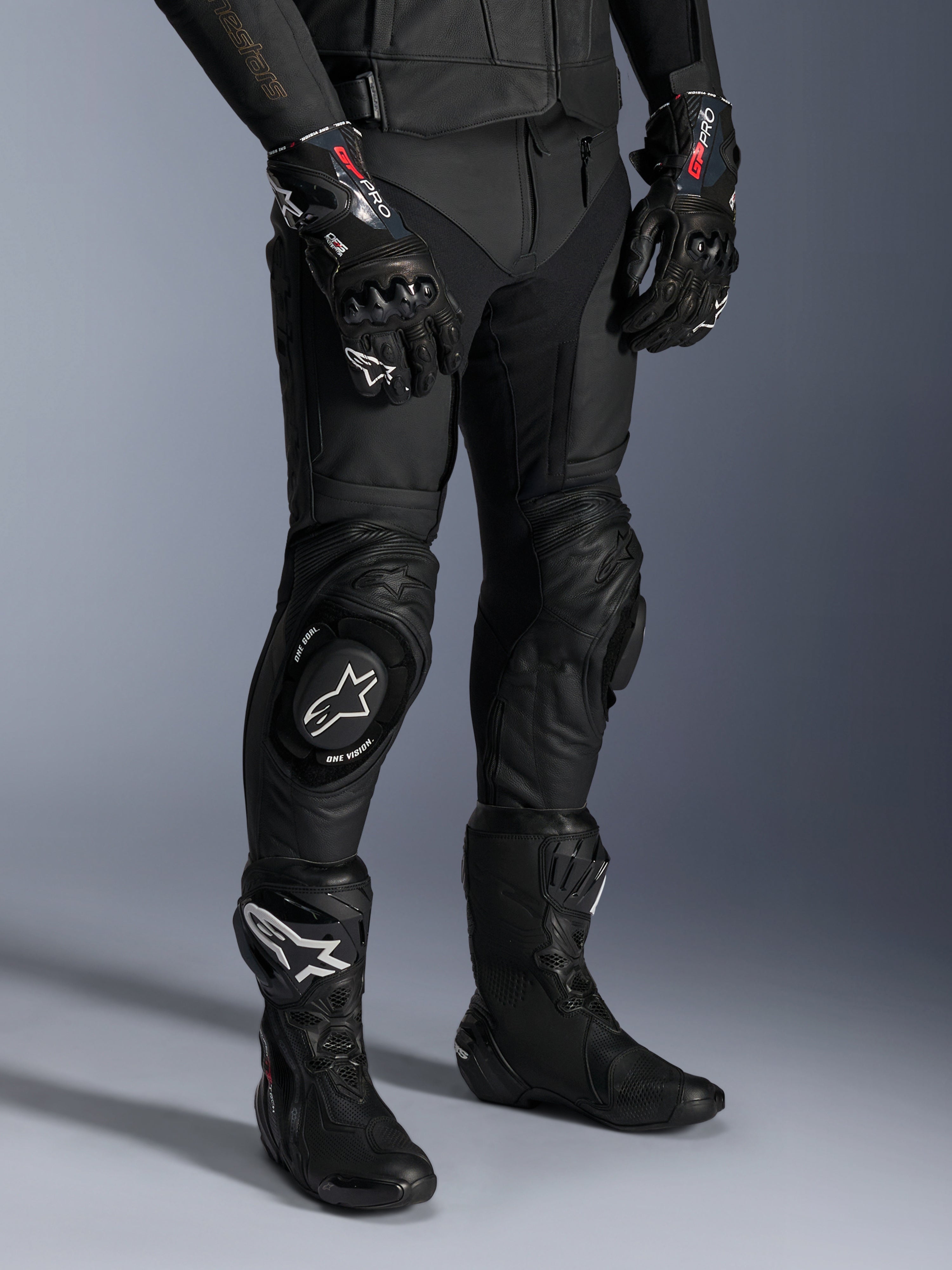 Alpinestars Missile V3, pantaloni da moto racing in pelle nera, indossati con guanti GP Pro e stivali da corsa tecnici, costruzione in pelle premium con saponette per ginocchio con logo bianco, estetica racing professionale per pista e strada