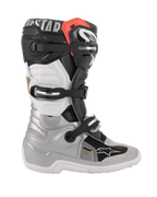 Stivali Alpinestars Youth Tech 7S, stivali da motocross, nero, argento, bianco e oro, vista laterale con scocca inferiore argento, pannelli superiori neri e bianchi, dettaglio rosso e sistema di chiusura a tre fibbie