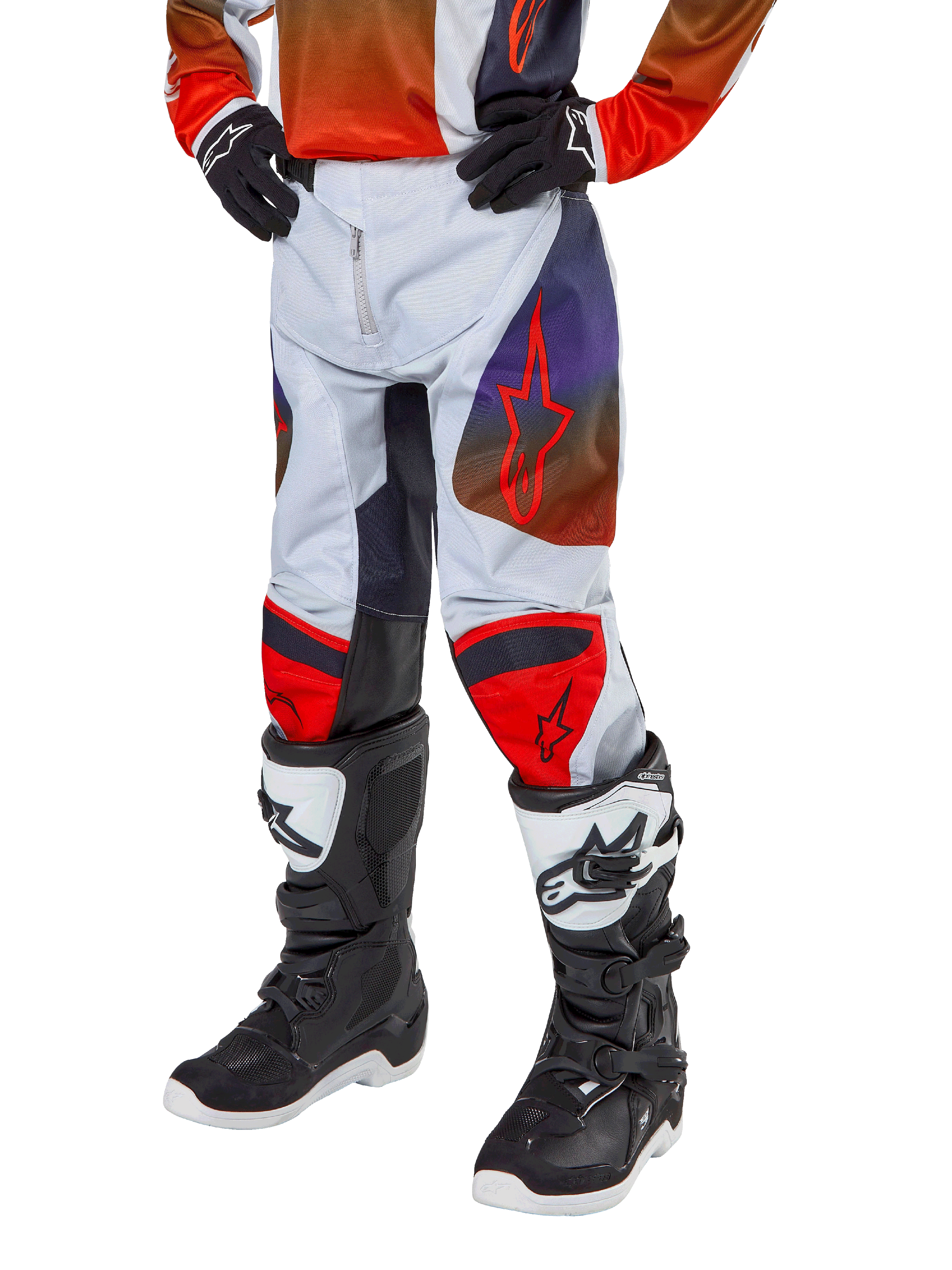 Alpinestars pantaloni Youth Racer Hoen 2024, pantaloni da motocross per ragazzi, grigio chiaro con accenti arancione acceso e nero, con loghi a stella rossi sulle cosce e pannelli rossi sulle ginocchia, indossati con stivali bianchi e neri, design resistente per corse fuoristrada