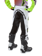 Alpinestars pantaloni Youth Racer Lucent 2024, pantaloni da motocross, bianco e nero con accenti neon, vista posteriore con ampio pannello elasticizzato e logo Alpinestars, indossati con stivali Alpinestars Tech Series bianchi e neri