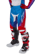 Alpinestars Youth 2024 Racer Pneuma Pants, pantaloni da motocross per ragazzi, blu, rosso e bianco, indossati con guanti e stivali abbinati, logo a stella bianco sulla coscia, design sportivo per fuoristrada