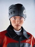 Alpinestars RSRV Onyx Beanie, berretto grigio scuro con dettagli ovali e logo bianco, indossato con giacca rossa e nera
