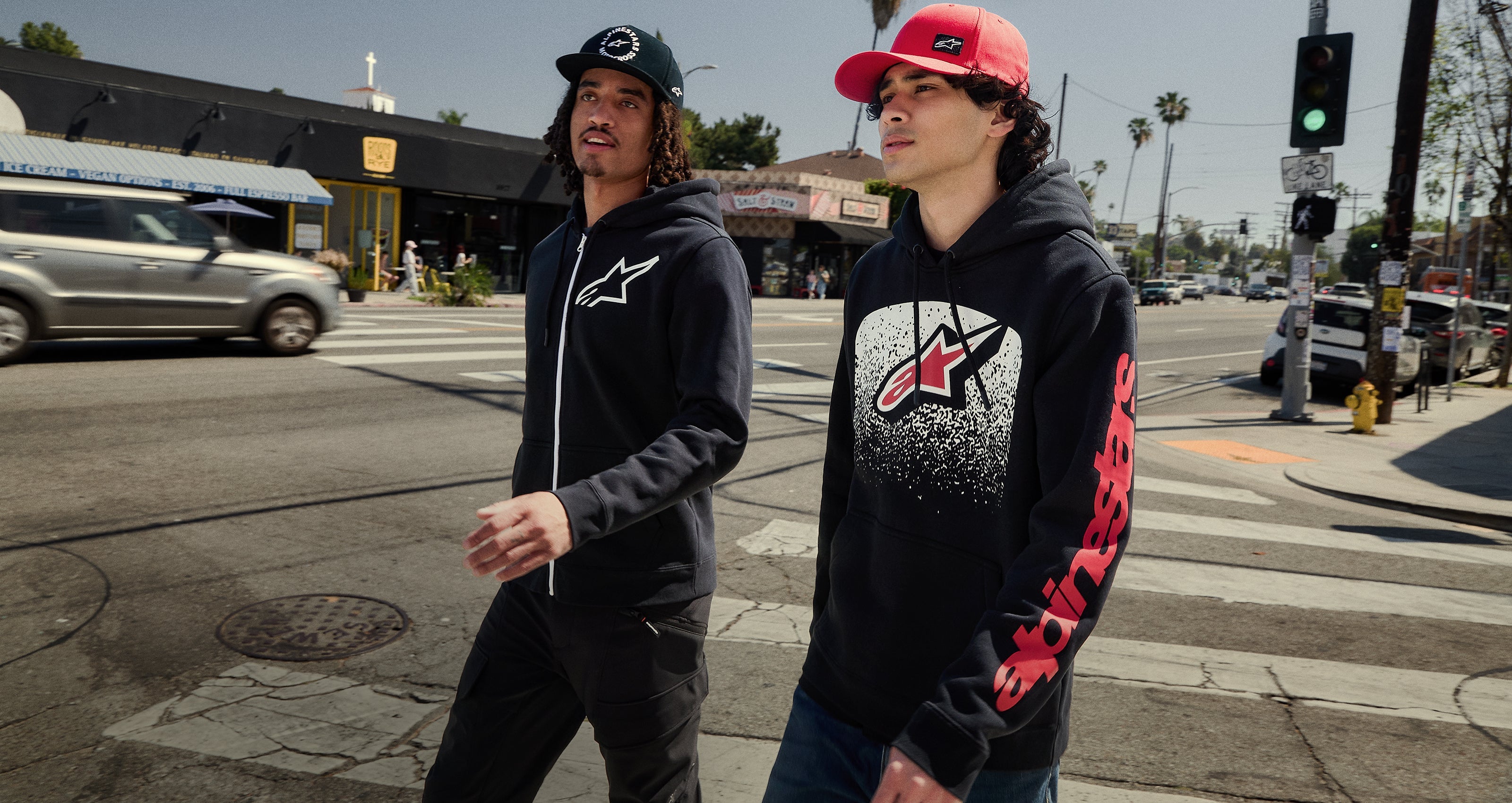 Alpinestars black and red hoodies and caps, worn in an urban city setting for casual lifestyle performance sportswear.