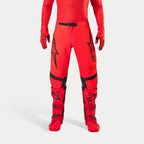 Pantaloni Alpinestars Supertech Ember LE, pantaloni da motocross, rosso fluo e rosso acceso con accenti neri, caratterizzati da vistosi loghi a stella neri sulle cosce, fibbia nera in vita e pannelli sulle ginocchia, indossati con stivali e guanti rossi coordinati per un completo da gara.